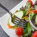 A Walco Saville stainless steel salad fork in a plate of salad.