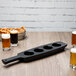 A black Libbey melamine flight paddle with beer glasses on it.
