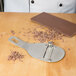 A Bron Coucke stainless steel chocolate shaver with chocolate shavings on a table.