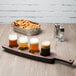 A Libbey Cherry Wood melamine flight paddle holding beer glasses on a table in a brewery tasting room.