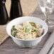 A white Thunder Group melamine bowl filled with noodles and peas on a table.