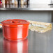 A Thunder Group red plastic rice container with a lid on a kitchen counter.