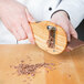 A person using a Bron Coucke wooden chocolate shaver to make chocolate shavings.