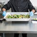 A chef holding a Western Plastics foil steam table pan filled with salad