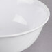 A close up of a white Thunder Group melamine swirl bowl with a white rim.