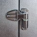 A stainless steel latch on a metal door with a metal hinge.