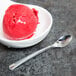 A white bowl of red ice cream with a Fineline silver plastic tasting spoon.
