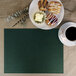 A green H. Risch Inc. faux leather rectangle placemat on a table with a plate of pastries and a cup of coffee.