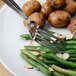 A plate of food including potatoes, green beans, and almonds with a Walco Maremma table fork.