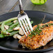 A Walco stainless steel flat handle fish fork on a plate of salmon.
