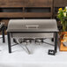 An outdoor buffet table with an Acopa food warmer lid on a stainless steel chafer.