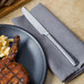 A plate of grilled meat and macaroni and cheese on a table with a Walco Freya stainless steel table knife.