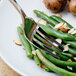 A Walco Freya stainless steel fork on a plate of green beans and potatoes.