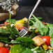 A Walco Freya stainless steel salad fork in a salad.
