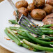 A Walco stainless steel dinner fork on a plate with potatoes and green beans.