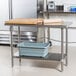 An Advance Tabco stainless steel work table with a cutting board on it.