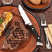 A steak on a plate with a Libbey Stockyard steak knife.