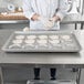 A woman in a chef's uniform making pastries in a Chicago Metallic ePAN.