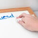 A hand using Expo Dry-Erase Board-Cleaning Wet Wipes to wipe blue writing off a white board.