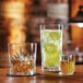 Two Arcoroc highball glasses filled with drinks on a table.