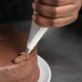 A close-up of a person using a Matfer Bourgeat nylon pastry bag to decorate a cake.
