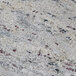 A close up of a Kashmir White granite stone surface with red and white spots.
