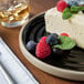 A slice of cheesecake with berries on a Chef & Sommelier Geode black stoneware plate.