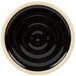 A close-up of a black Chef & Sommelier Geode stackable plate with a black circular rim.