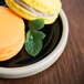 A Chef & Sommelier black stoneware plate with two macarons and mint leaves.