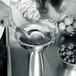 A person using an iSi stainless steel funnel with sieve insert to strain raspberries.
