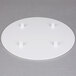 A white circular Wilton cake separator plate with four holes.