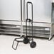 A black hand truck with wheels and a handle for a Sterno Insulated Food Carrier.