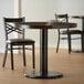 A round table with a black Lancaster Table & Seating Cast Iron table base and plates on it.