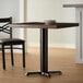 A Lancaster Table & Seating black cast iron table base with a wooden table top and chairs.