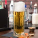 A Libbey Frankfurt beer mug full of beer with foam on top sitting on a table.