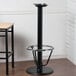 A Lancaster Table & Seating black cast iron bar height table base with a foot ring.