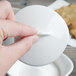 A hand holding a white Villeroy & Boch porcelain sugar bowl with cover.