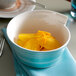 A Villeroy & Boch Amarah aquamarine porcelain bowl filled with orange slices on a table.