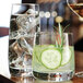 A Chef & Sommelier cooler glass filled with water and cucumber slices on a table.
