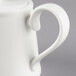 A close-up of a white Villeroy & Boch teapot with a handle.