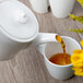 A Villeroy & Boch white porcelain teapot pouring tea into a cup.