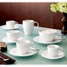 A group of white Villeroy & Boch Dune saucers with coffee cups on a table.