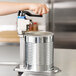 A person using a Vollrath Redco EaziClean heavy duty can opener to open a metal can.