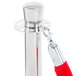 A Lancaster Table & Seating silver crowd control stanchion pole with red rope and handle.
