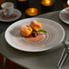 A Villeroy & Boch taupe porcelain coupe plate with dessert on a table.