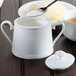 A spoonful of sugar being poured into a Villeroy & Boch white porcelain sugar bowl.