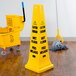 A Rubbermaid yellow caution wet floor cone in a room with a mop and bucket.