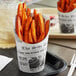 A Choice paper scoop cup with a newsprint design filled with french fries.