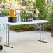 A Lancaster Table & Seating granite white folding table with drinks and bottles on it.
