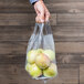 A hand holding a Polypropylene soft loop handle bag of apples.